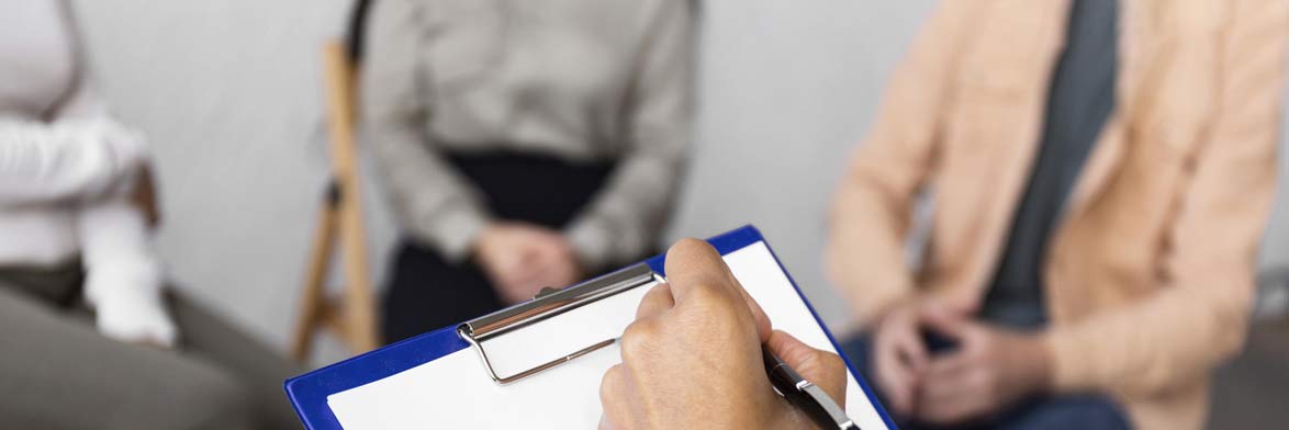 woman writing down clipboard group therapy session